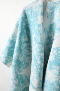 Detail of light blue and white ink painting pattern on soft cashmere shawl with fringe