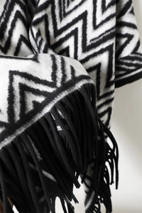 Detail of black and white geometric wave knit fabric with thick tassels and soft texture