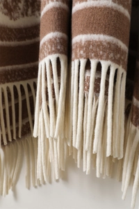 Detailed view of the thick faux cashmere texture and elegant tassels on a brown striped shawl