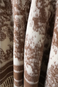 Detailed macro view of the ink wash pattern and soft tassel edges on the wool shawl