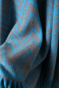 Close-up of blue and grey zigzag patterned cashmere shawl with soft knit fringe tassels