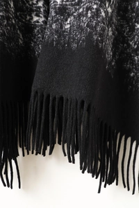 Detailed macro view of black and white patterned shawl with elegant long tassel fringes