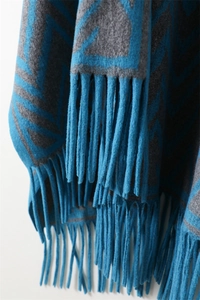 Detailed view of peacock blue geometric jacquard fabric with thick matching fringe tassels