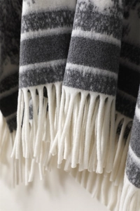 Macro shot of faux cashmere shawl with gray and white jacquard pattern and tassel detail
