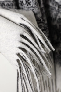 Close-up of thick black and white patterned shawl with elegant tassel fringe detail