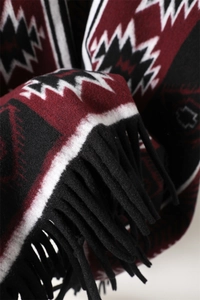 Detailed macro view of geometric knit fabric and thick black fringe tassels on the scarf