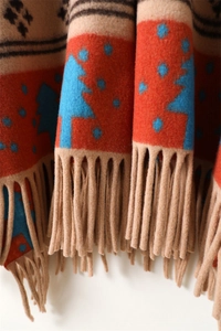 Close-up of geometric deer knit scarf with festive patterns and dense fringe details