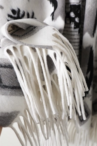 Dettaglio di uno scialle con motivo geometrico a fiocco di neve e lunghe nappe decorative