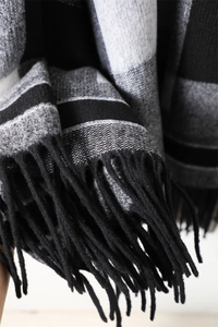 Detail of British plaid cashmere-like scarf with thick black fringe tassels on the edge
