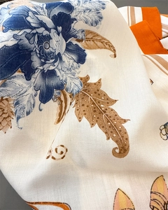 Close-up of herringbone texture on silk-like floral scarf with blue peonies and orange accents