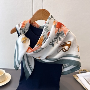 Detail of floral faux silk scarf with retro watch patterns tied on a navy knit vest