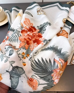 Detailed view of floral silk scarf with orange peonies and vintage golden crest patterns
