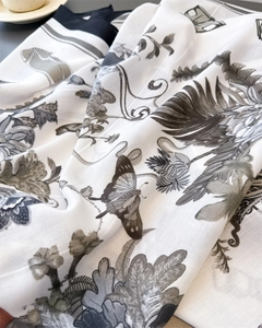 Macro shot of silk-like scarf fabric showing detailed butterfly and floral prints