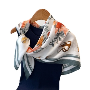 Silk-like floral square scarf with orange blossoms and geometric border on wood hanger