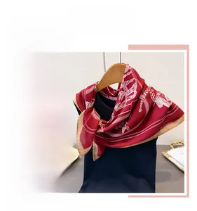 Detail view of the deep red square silk scarf with baroque floral patterns and golden border