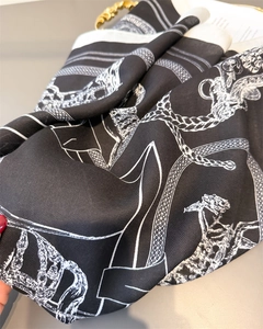 Detail showing the herringbone weave texture and equestrian chain pattern on silk scarf