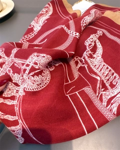 Detail of red equestrian silk scarf with herringbone texture and horse chain prints