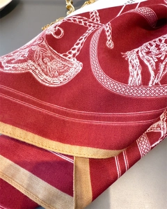 Macro detail of red equestrian silk scarf showing herringbone texture and horse bridle pattern