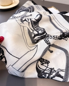 Detail of equestrian print silk scarf showing horse motifs and twill texture in hand