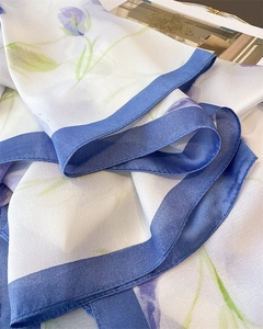 Detail of silk-like scarf with purple tulip floral print and blue contrast borders