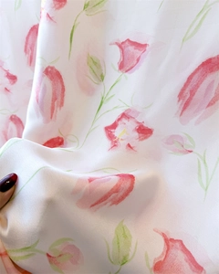 Detail of glossy silk satin fabric featuring red and pink floral watercolor patterns