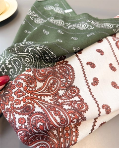 Detailed view of bohemian paisley patterns on linen-textured scarves in olive and cream