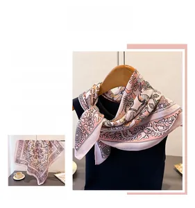 Detailed pattern of a pink herringbone silk scarf with floral and bird motifs