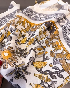 Detailed view of cream silk scarf with forest motifs and hand-rolled edge craftsmanship