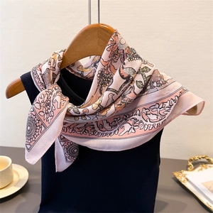 Pink herringbone silk-like scarf with forest animal and floral print on a wooden hanger