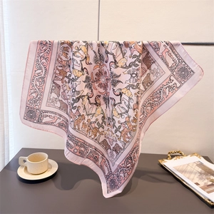 Light pink herringbone silk scarf with animal and floral patterns hanging on a metal rod