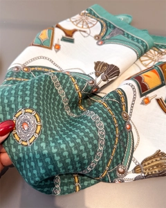 Detailed view of luxury silk scarf with vintage carriage and chain prints in green and gold
