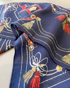 Macro detail of navy herringbone scarf with vintage gold chains and royal jewel patterns