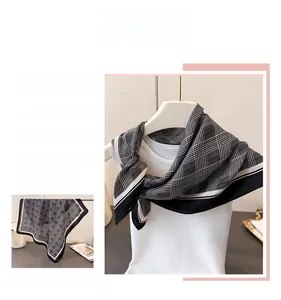 Detailed view of black and white houndstooth plaid silk scarf draped on a mannequin