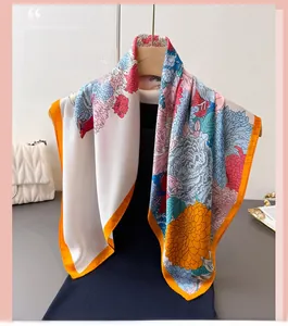 Detailed view of floral silk scarf featuring hand-rolled orange edges on wooden hanger