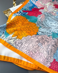 Detailed view of floral silk scarf featuring vibrant orange rolled edges and smooth texture