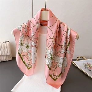 Pink and green floral faux silk scarf hung on a white sweater for outfit display