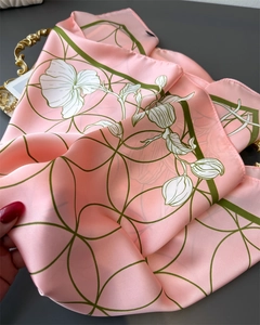 Detail of pink silk-like scarf with floral patterns and satin luster on golden tray