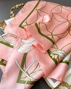 Close-up of pink silk scarf with floral and geometric patterns on a vintage gold tray