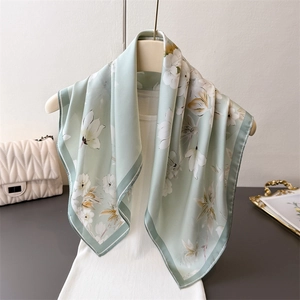 Elegant mint green silk scarf with yellow floral prints and dark green border on mannequin