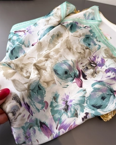 Detailed view of floral silk scarf folded on tray showing fabric texture and sheen