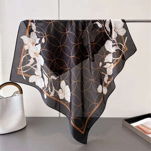 Detailed texture of black and gold floral silk scarf showing elegant drape and semi-sheer fabric