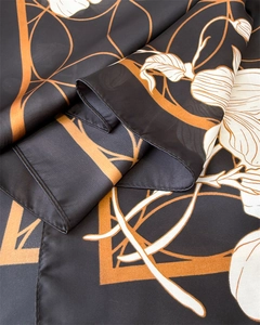 Detail of silk-like floral scarf with elegant black and orange patterns and rolled edges