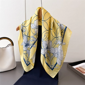 Close-up of elegant yellow silk scarf with blue floral prints and geometric art lines