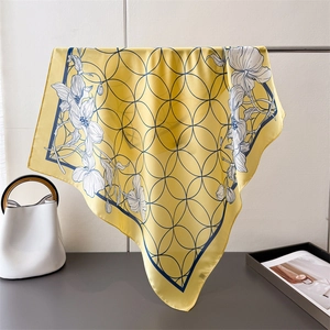Detail of yellow silk scarf with floral and geometric patterns hanging on a rack