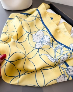 Detail of floral and geometric print yellow silk scarf with elegant drape and luster