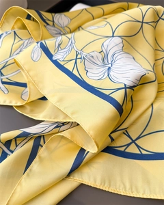 Macro detail of floral silk scarf featuring bright yellow fabric and fine edge stitching