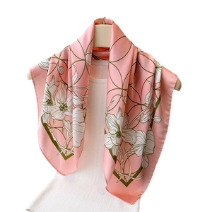 Elegant floral silk scarf with pink floral and green geometric patterns on display