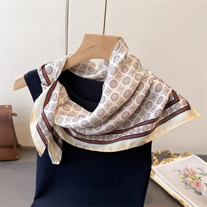 Elegant geometric print silk-like scarf with vintage patterns tied on a black knit top