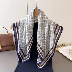 Elegant geometric print silk-like square scarf with navy blue border on wooden hanger