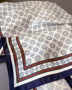 Close-up of geometric floral print silk scarf with navy borders and elegant folding